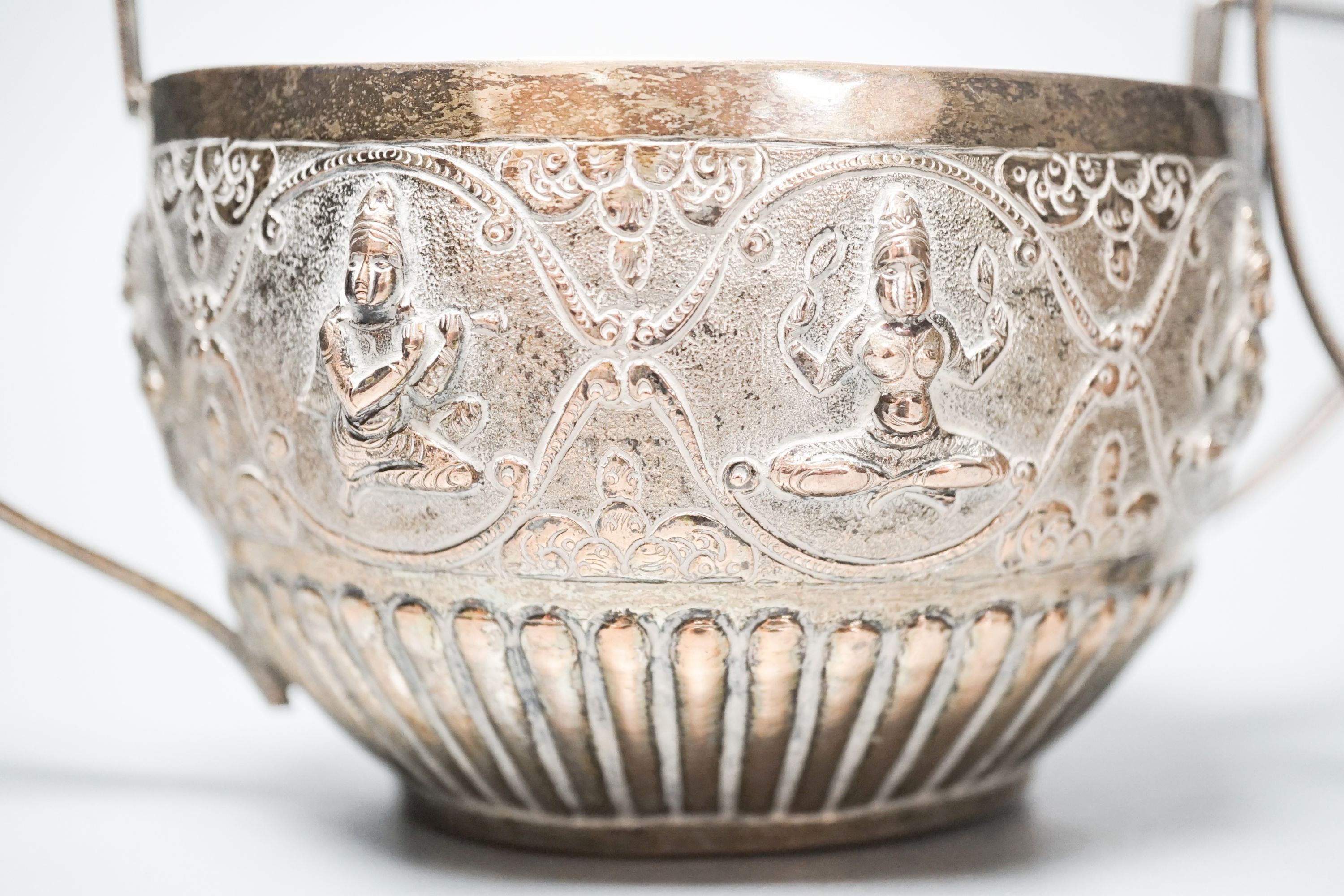 An Indian white metal sugar bowl and cream jug, embossed with deities, 8.5oz.